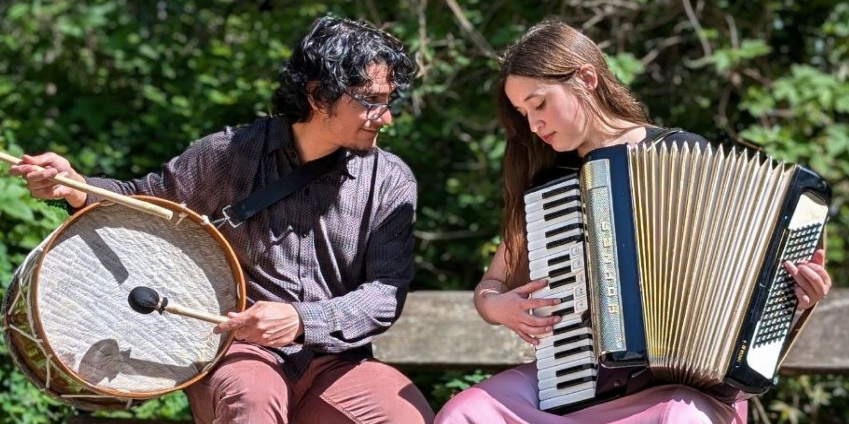 Víctor Gutiérrez und Isidora Caroca sitzen auf einer Bank. Während Víctor ein Schlaginstrument hält, hat Isidora ein Akkordeon., © Dúo Pequén Víctor Gutiérrez und Isidora Caroca sitzen auf einer Bank. Während Víctor ein Schlaginstrument hält, hat Isidora ein Akkordeon., © Dúo Pequén