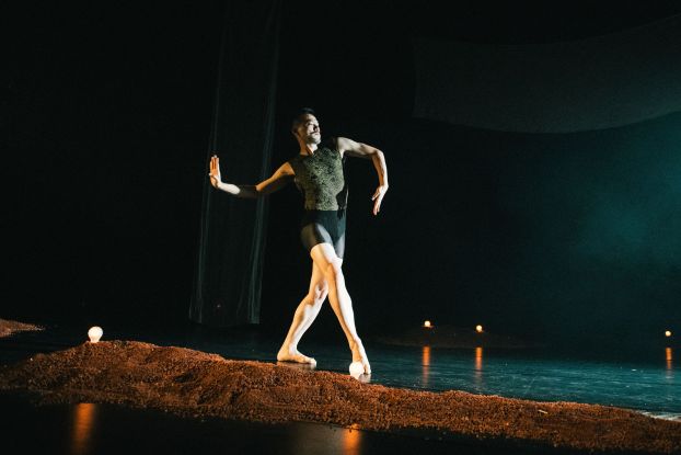 Ausschnitt aus der Tanzproduktion »Choreographing Story »Rama House«« von Chen Wu-kang und Pichet Klunchun. Eine performende Person bewegt sich in einer Ballett-Pose über die Bühne. Vor ihr ist ein kleiner erdartiger Hügel aufgescharrt., © Candy Weltz Ausschnitt aus der Tanzproduktion »Choreographing Story »Rama House«« von Chen Wu-kang und Pichet Klunchun. Eine performende Person bewegt sich in einer Ballett-Pose über die Bühne. Vor ihr ist ein kleiner erdartiger Hügel aufgescharrt., © Candy Weltz