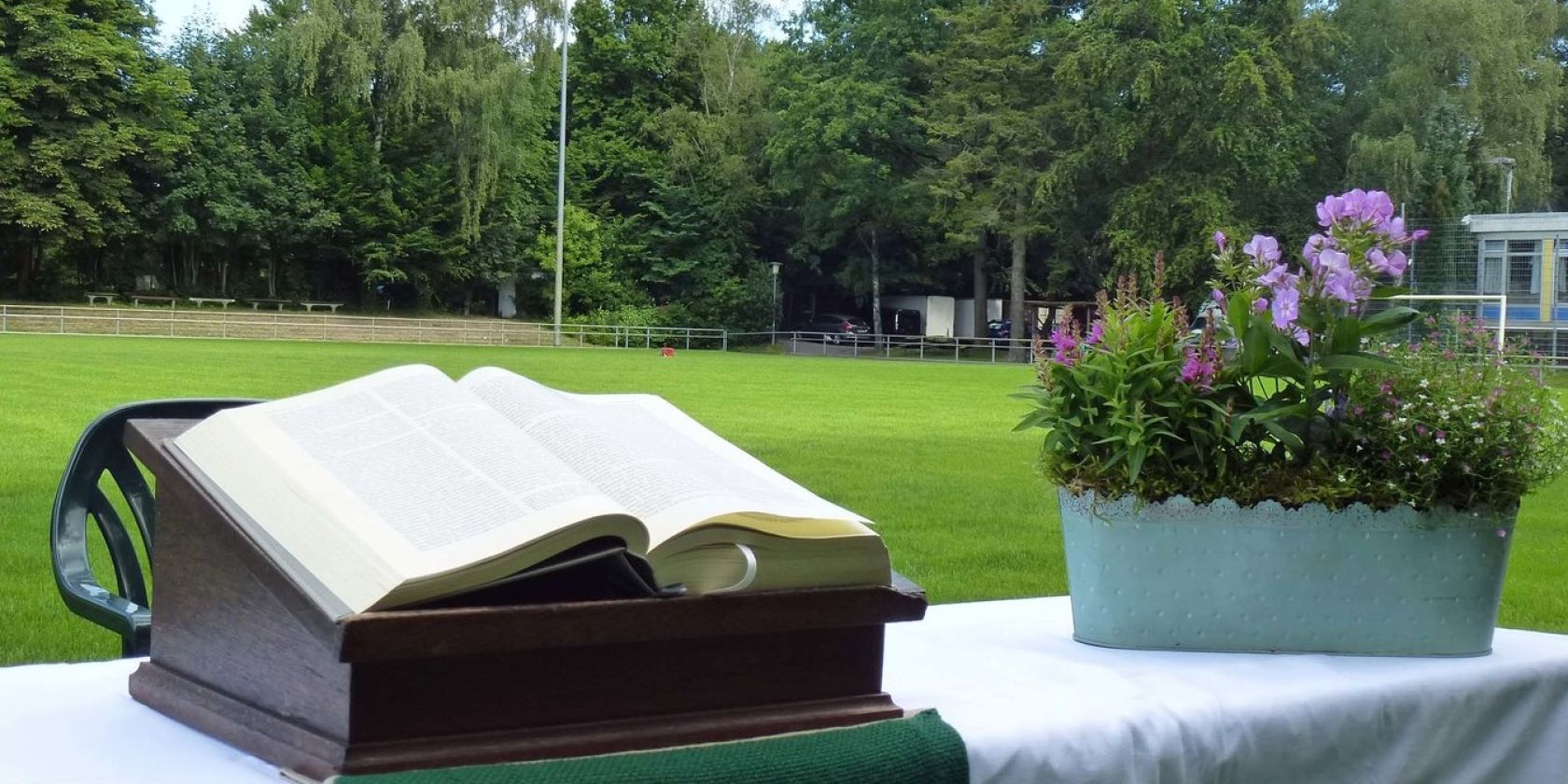 Aufgebauter Altar mit Bibel und Blumenschmuck auf einem Fußballfeld, © Karen Diehn Aufgebauter Altar mit Bibel und Blumenschmuck auf einem Fußballfeld, © Karen Diehn