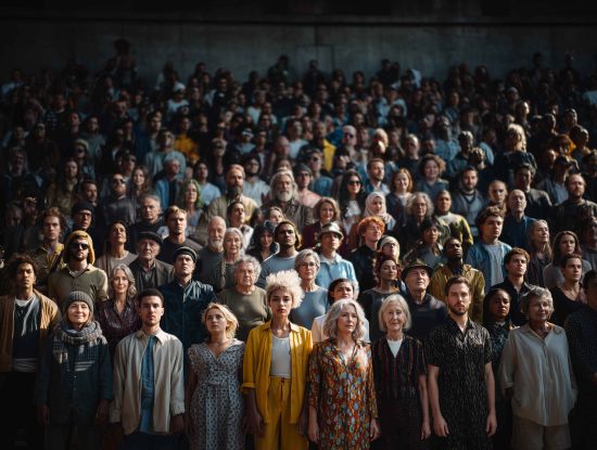 Eine Menschenmenge die in die Kamera schaut, &copy; Grafik: Basics09  KI-generiert