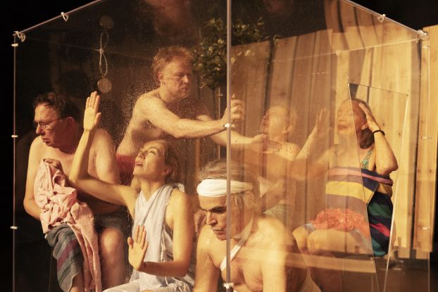 Six performers are in a sauna setting behind a glass wall. They are all in different positions and scantily clad., &copy; Armin Smailovic