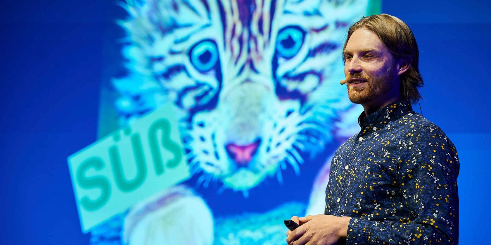 Mann der vor einer Leinwand steht auf der eine Pr&auml;sentation l&auml;uft in der ein Katzenbaby zusehen ist, &copy; Claudia H&ouml;hne