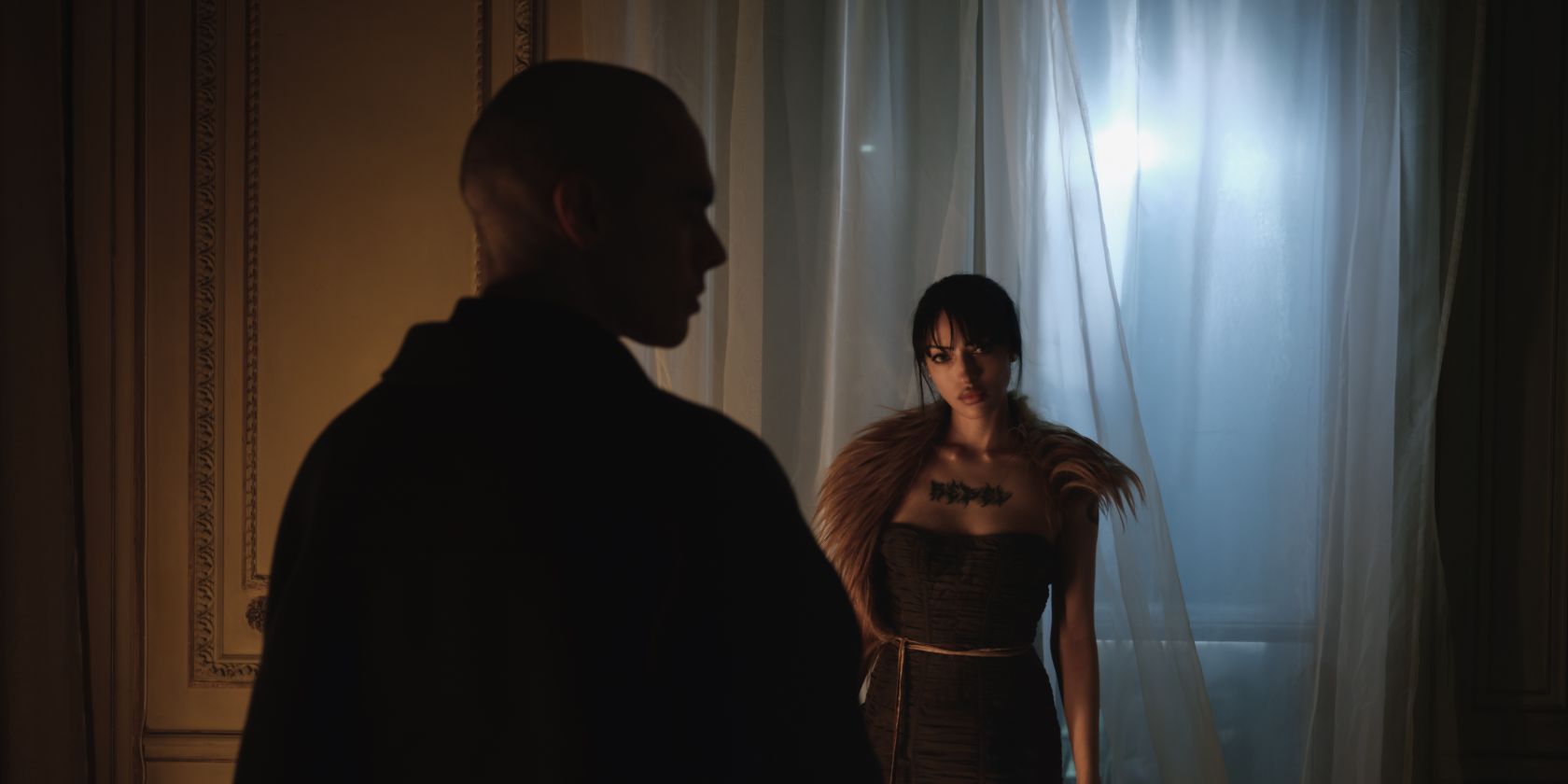 Zwei Personen in einem dunklen Raum. Die eine Person ist von hinten zu sehen, die andere blickt in die Kamera. Sie hat ein Fell um die Schultern gelegt., &copy; Kiss Facility