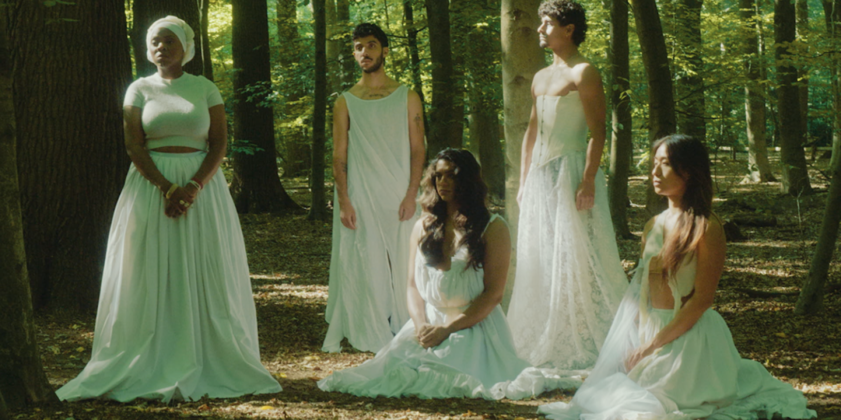 Five performers in long white dresses pose in the forest. Three of them are standing, two are sitting on the ground. None of them are looking at the camera., &copy; Danny Shin