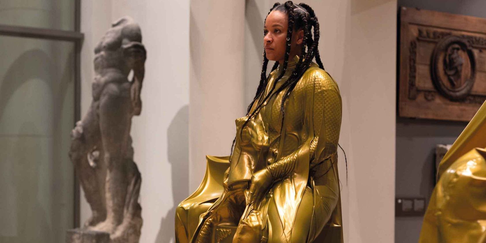 A person wearing a shiny gold-colored suit is on display as an exhibit in the museum., &copy; Sarah Estio